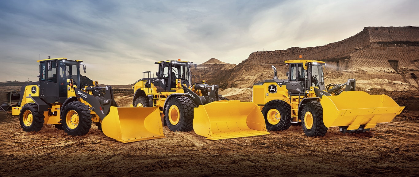 Três pás-carregadeiras de rodas John Deere no deserto.