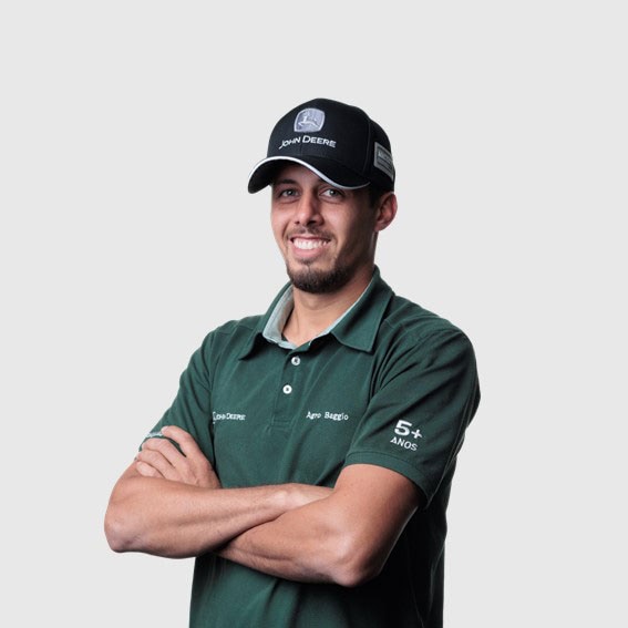 Guilherme Schuster com braços cruzados vestindo um boné preto e uma camisa verde.