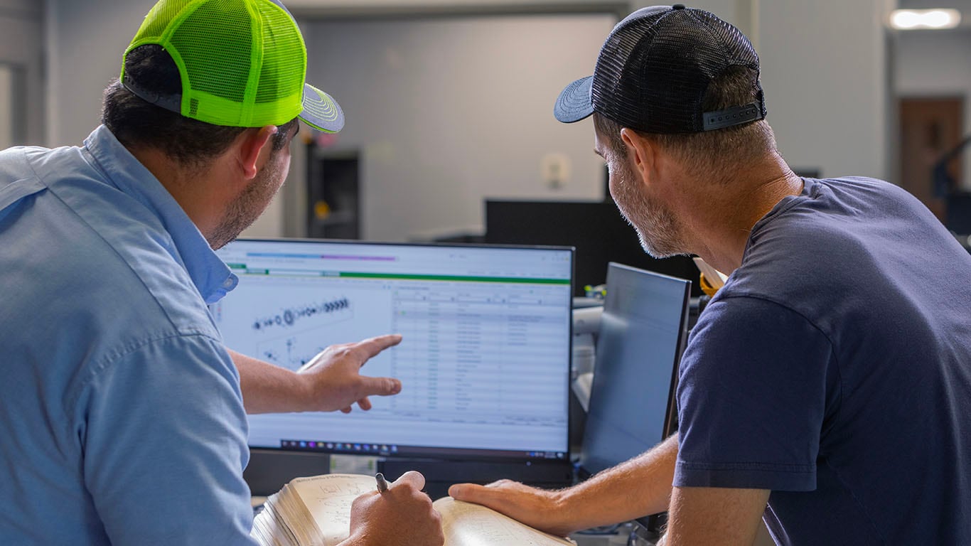 Dois homens olhando para a tela do computador.