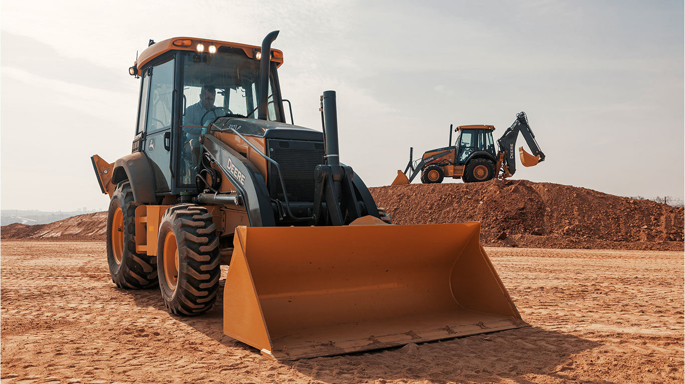 Duas Máquinas Retroescavadeira 310 em terra planta