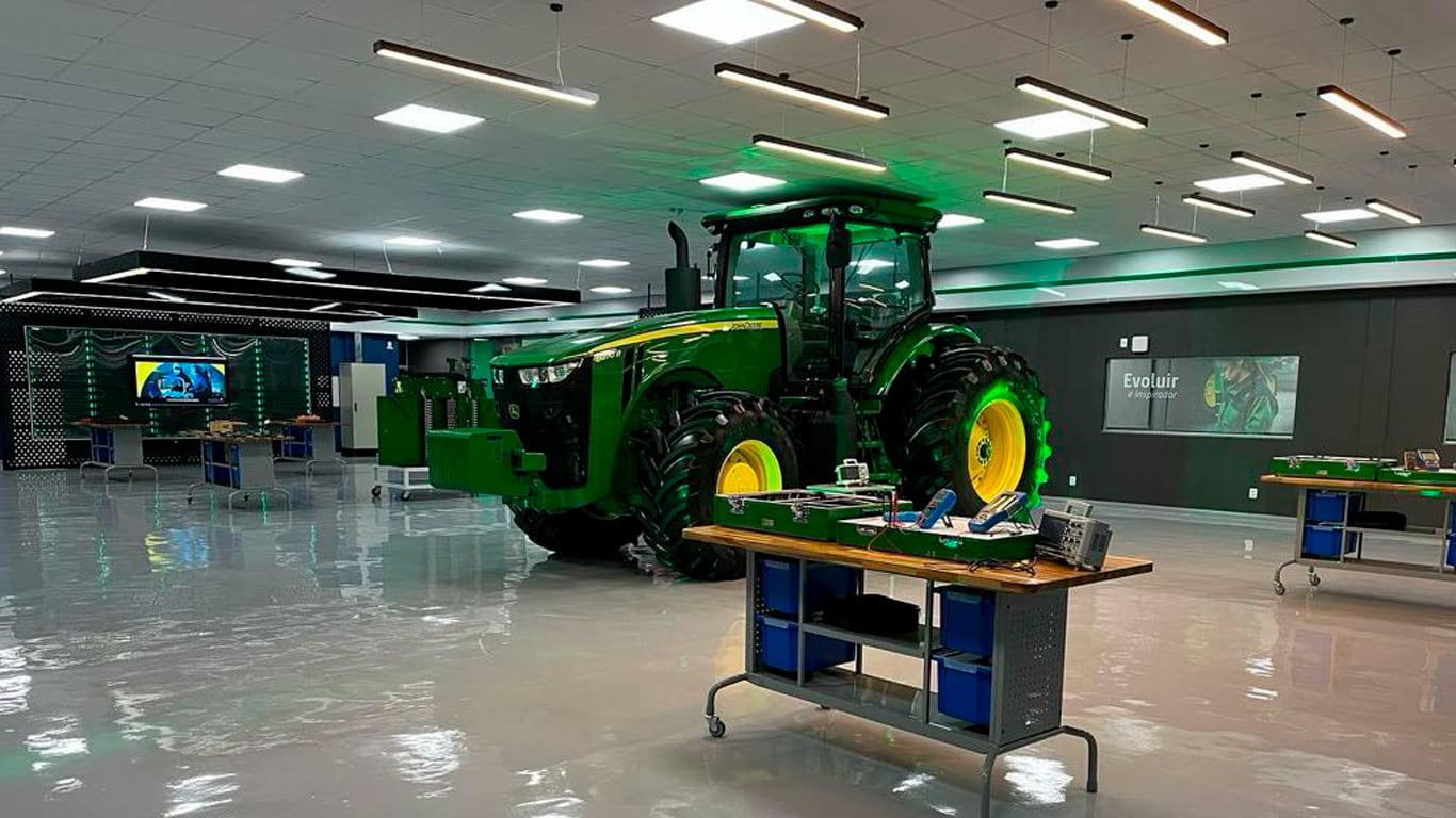 Na foto é possível ver uma sala de aula dentro de um dos Centro de Treinamentos da John Deere com um trator dentro.