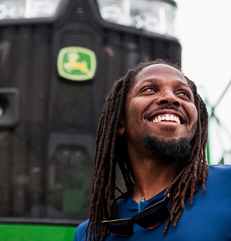 Funcionário sorrindo na frente de um trator