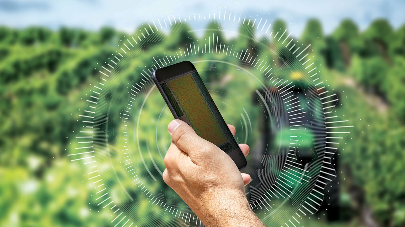 Homem segurando um celular no campo.