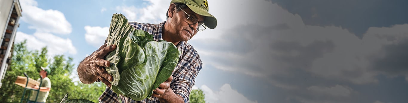 Um homem de capacete em um canteiro de obras com equipamentos John Deere ao redor