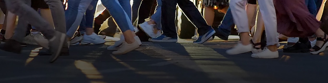 Uma faixa de pedestres na cidade, mostrando dezenas de pessoas caminhando em direções opostas enquanto atravessam a rua