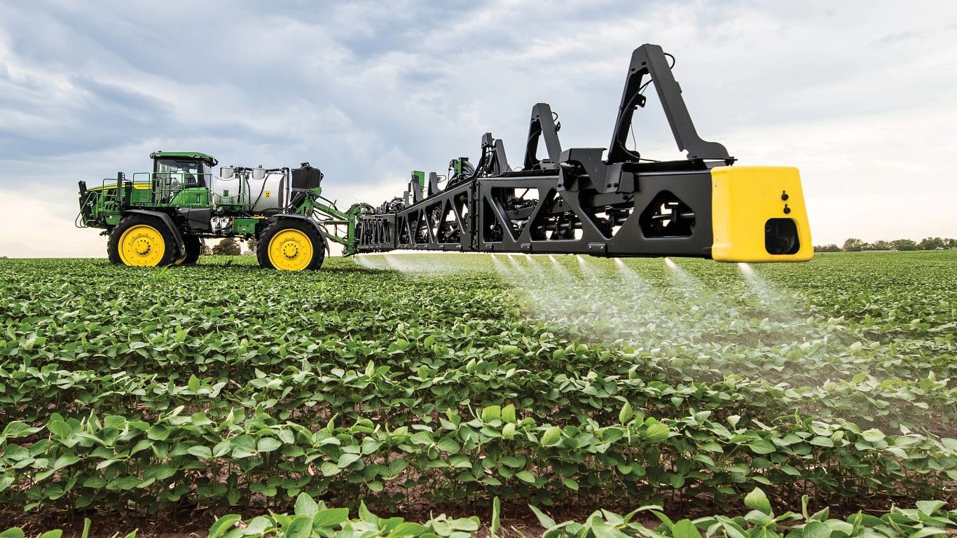 Vista em close de uma barra de pulverizador da John Deere em um campo aberto.