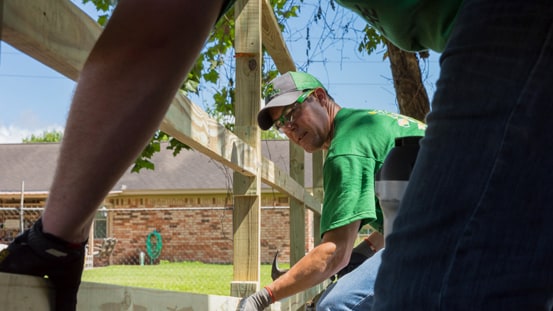 Duas pessoas juntas construindo uma cerca perto de um edifício.