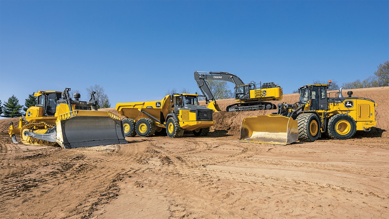 Vários veículos de construção da Deere em terrenos sujos