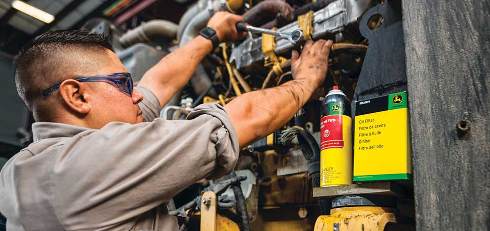 Um técnico trabalha com fluidos da John Deere em um equipamento