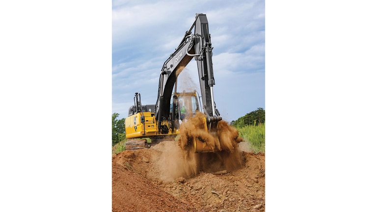 Um operador usando uma Escavadeira Tier P 210 para remover terra com um campo verde e árvores no fundo.