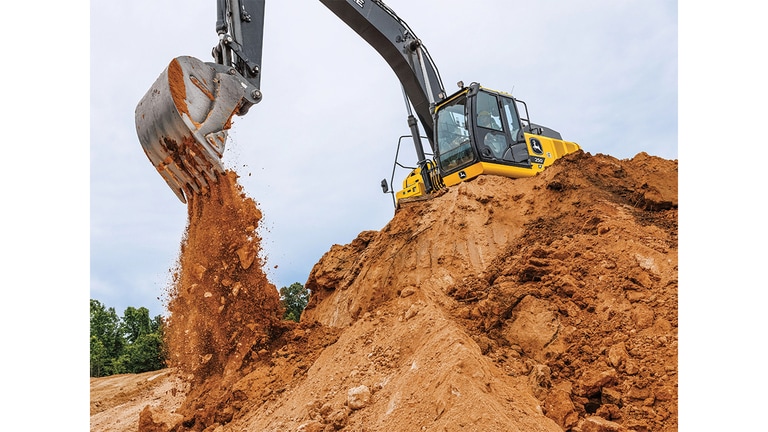 Uma Escavadeira 250 Tier P despeja terra em um poço a partir do topo de uma pilha.