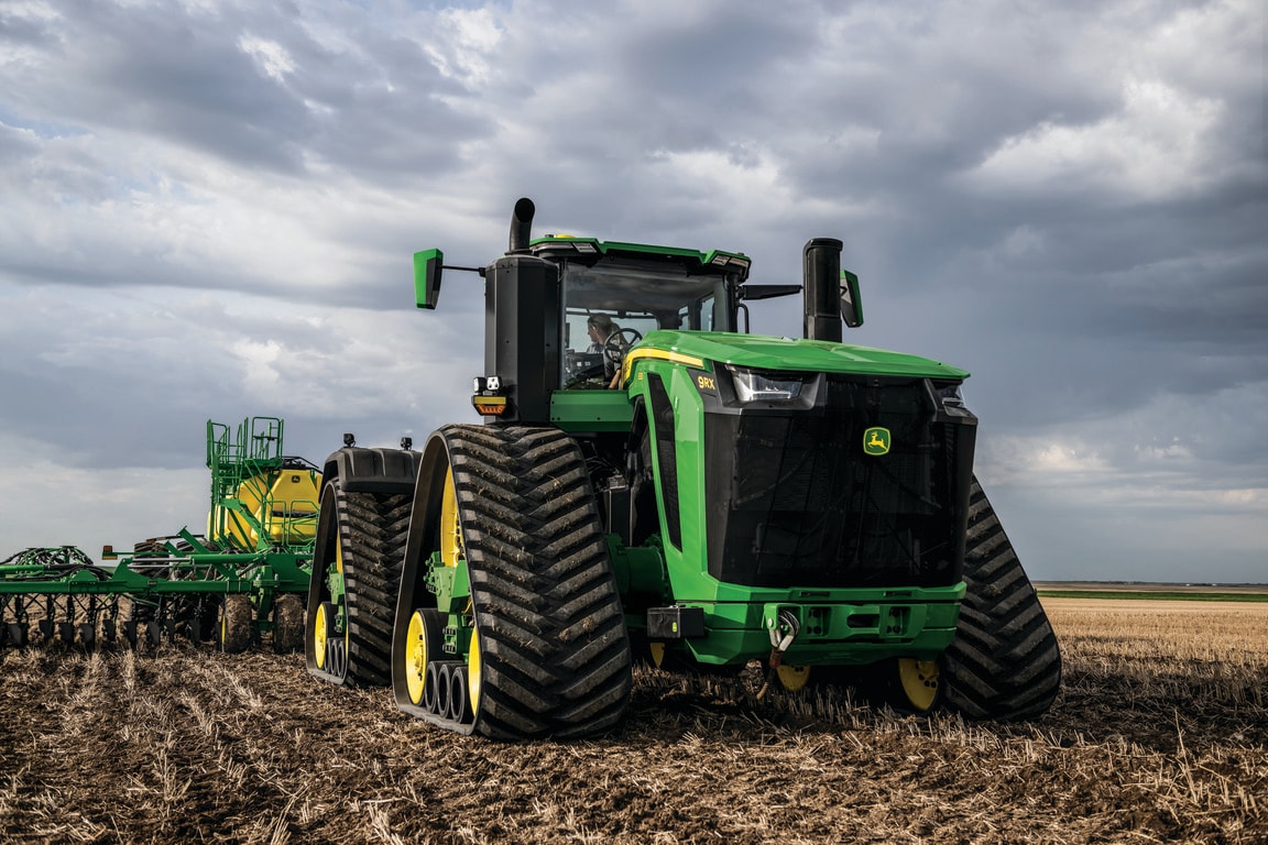 O trator modelo 9RX, equipado com largas esteiras, está em plena operação em um terreno seco.