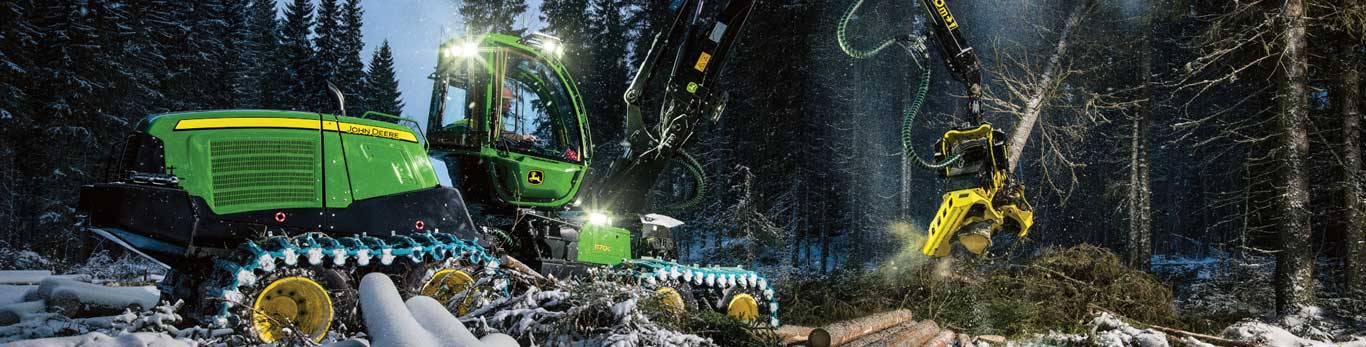 A Harvesters de Pneus John Deere 1170G funciona em uma área arborizada coberta de neve