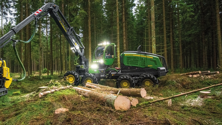 Harvester de pneus 1270G movendo troncos de árvores em uma floresta.