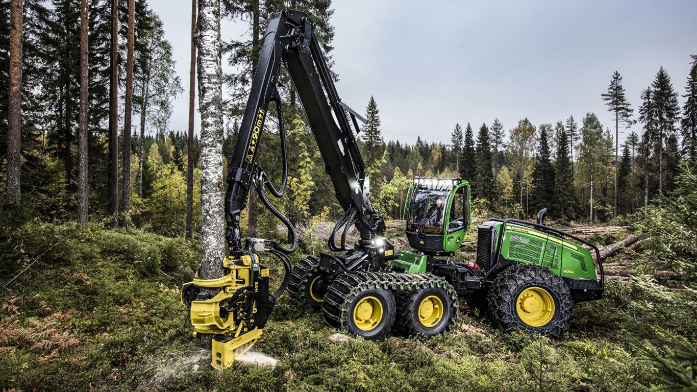 Harvester de pneus 1470G movendo um tronco de árvore em uma floresta.