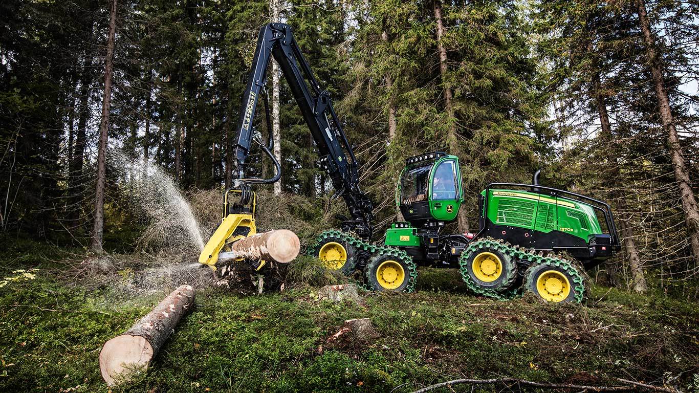 Harvester de pneus 1270G cortando um tronco de árvore em uma floresta.