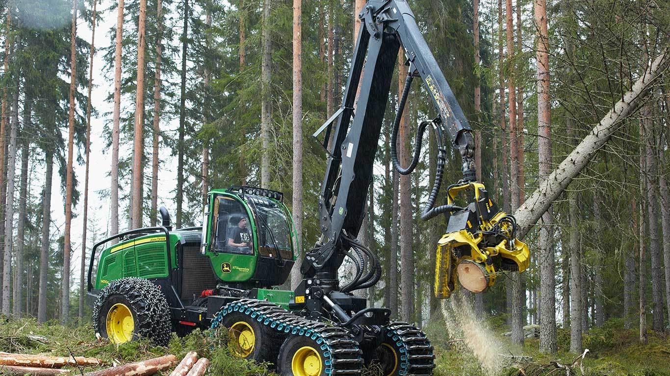 Harvester de pneus 1470G movendo um tronco de árvore em uma floresta.