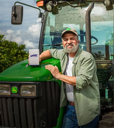 Homem na frente de um trator John Deere, com uma caixa da Unimil.