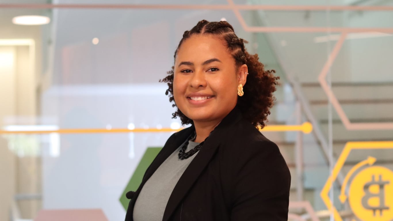 Mulher negra sorrindo olhando para a frente utilizando um blazer preto