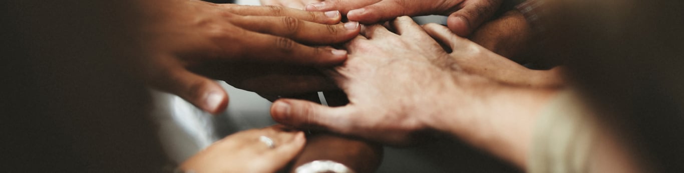 Mãos de pessoas brancas e negras em cima umas das outras simbolizando união