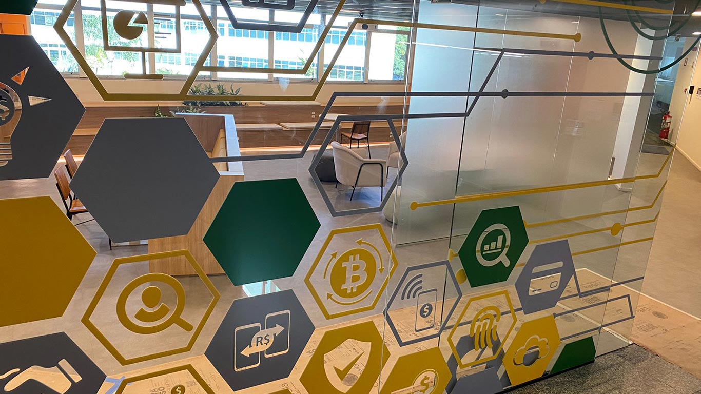entrada feita de vidro com varios adesivos de itens tecnológicos do Banco John Deere
