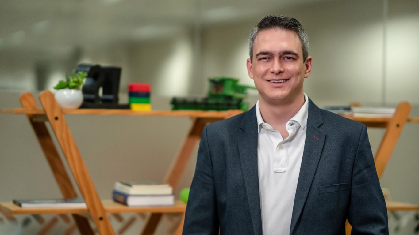 Pessoa em pé (Rodrigo Bonato) em um ambiente interno, vestindo um blazer escuro sobre uma camisa polo branca.