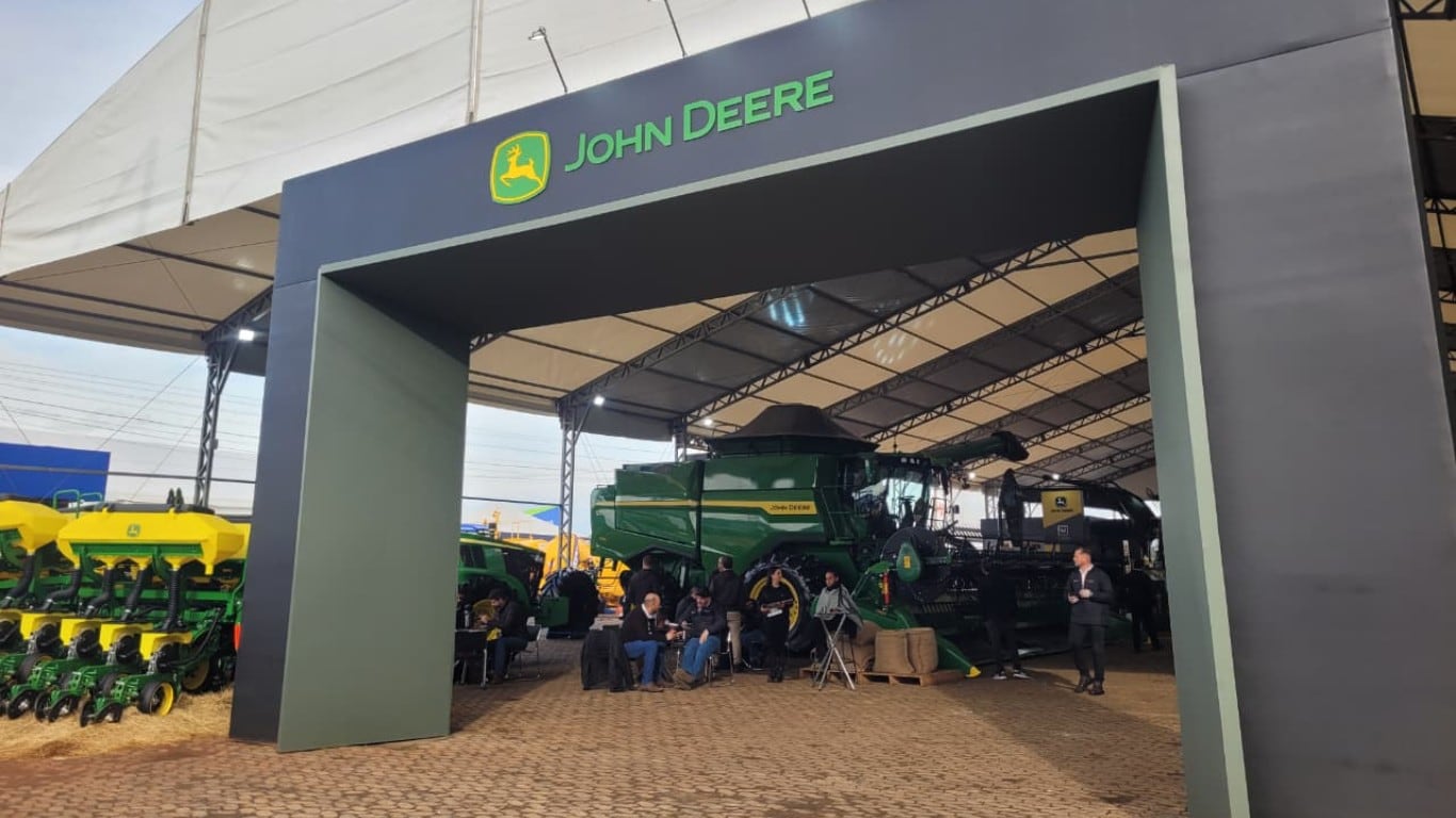 Vista a partir do topo de uma máquina agrícola verde em uma extensa lavoura de grãos.