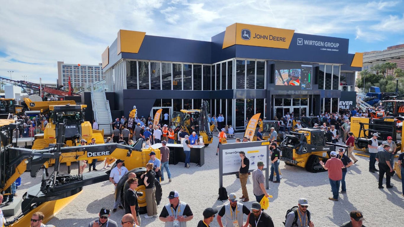 Estande da Deere ao ar livre com máquinas de construção e visitantes.
