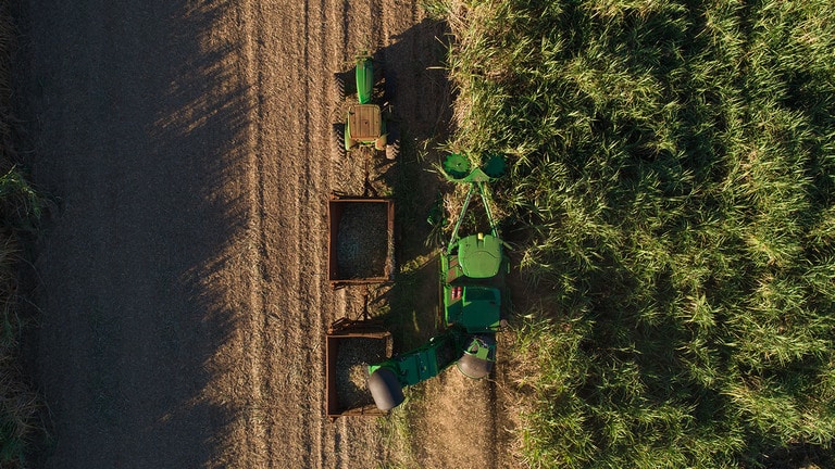 Foto aérea da colhedora cana john deere modelo ch950 com duas linhas de corte de cana no campo