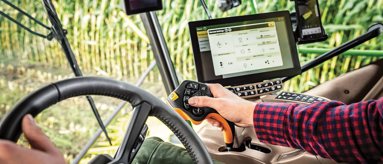 Mão operando o controle da forrageira com um joystick CommandPRO™.