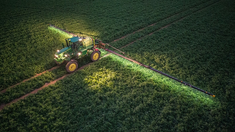 Pulverizador M4030 em campo durante a noite.