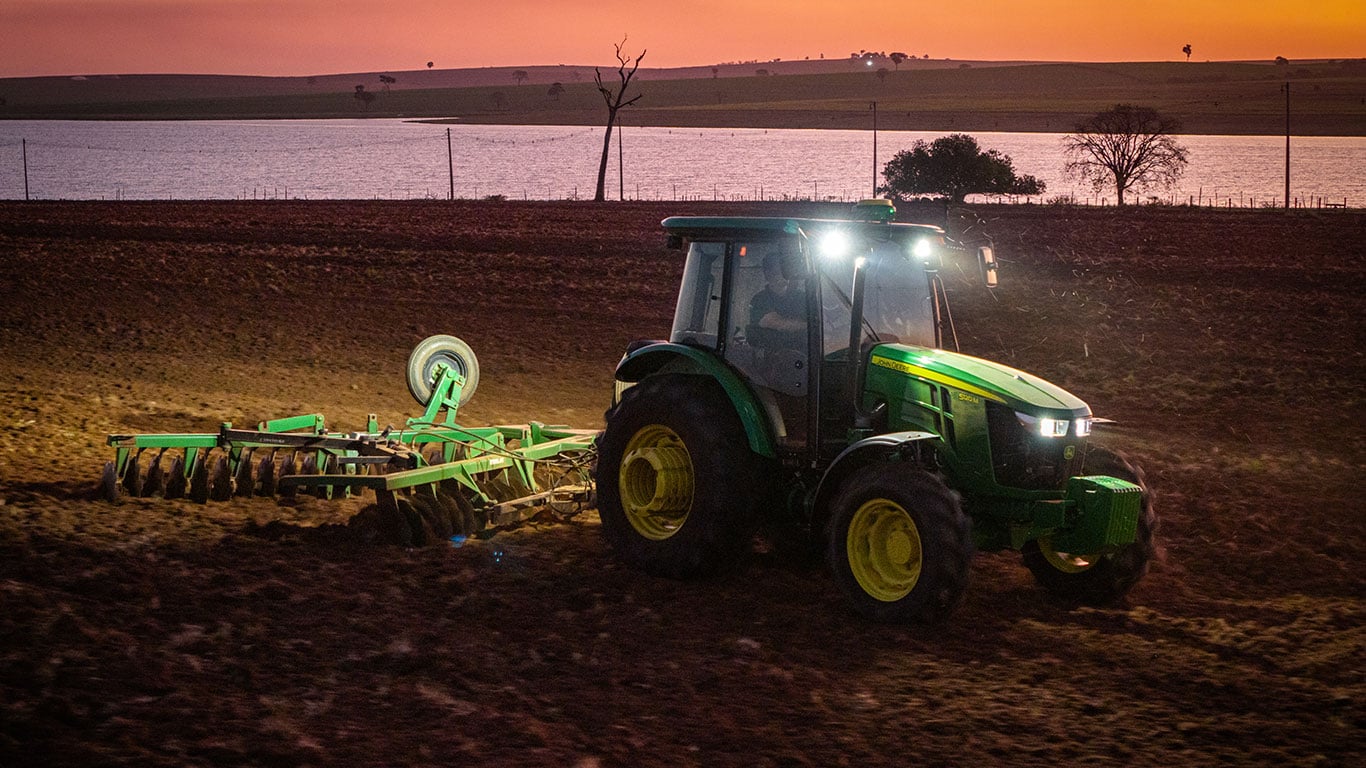 Trator da linha 5M com as luzes de LED acessas a noite.