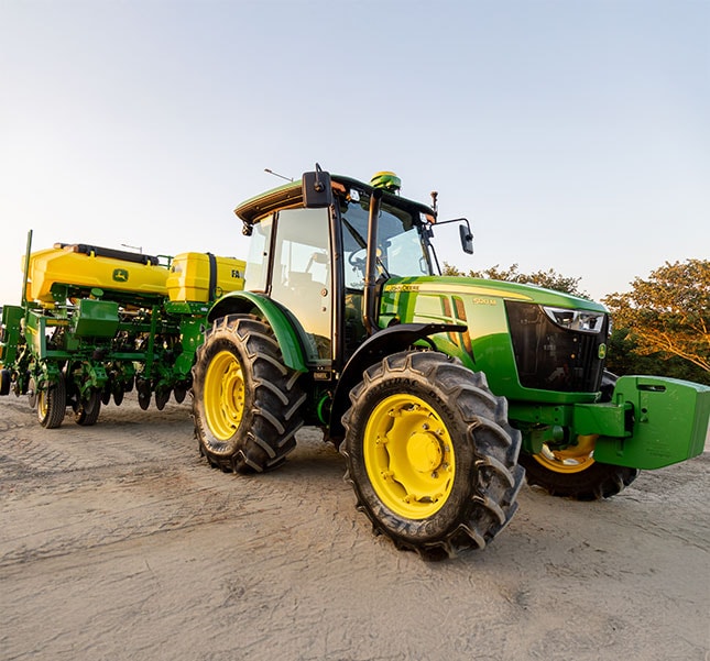 Trator 5120M com uma plantadeira no campo.