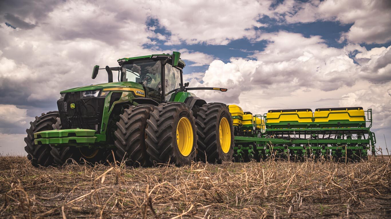 Trator 8R 490 John Deere no campo.