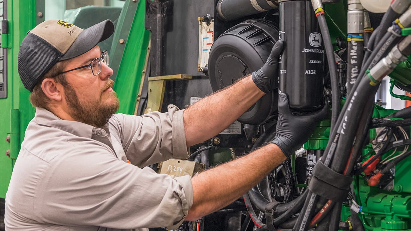 Técnico que faz manutenção na máquina John Deere e substitui o filtro